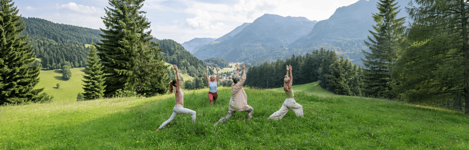 Yogagruppe übt im Freien auf einer Bergwiese im Chiemgau, im Hintergrund Alpenpanorama