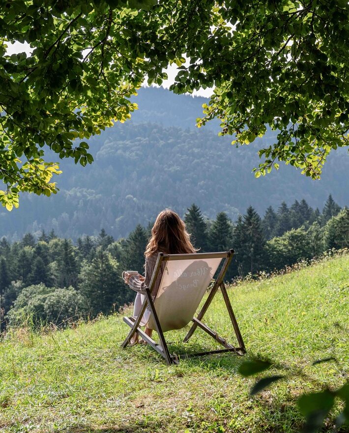 Person sitzt draußen mit Blick auf die Chiemgauer Berge